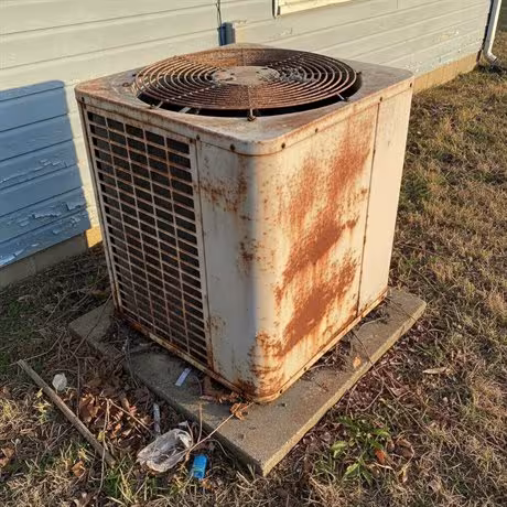 An old, rusty HVAC condenser unit that needs replacing
