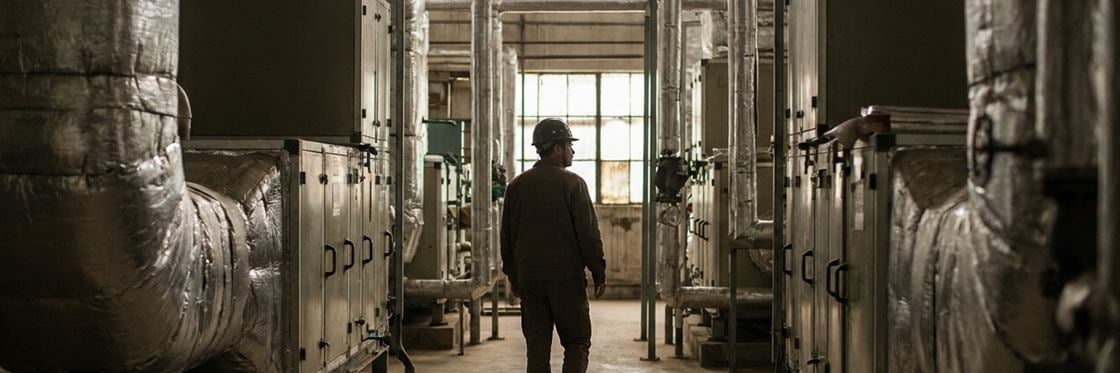 A commercial mechanical plant room with large air handling units and ductwork.