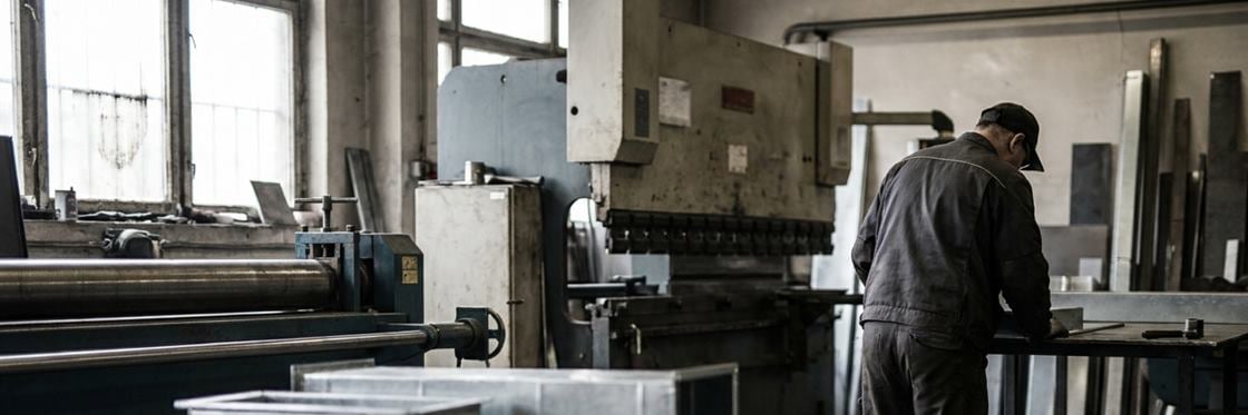 A fabrication workshop with formed galvanised duct sections stacked on a pallet.