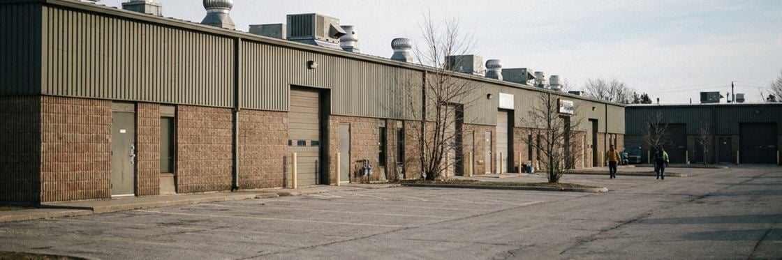 A row of separate single-storey commercial units in a light-industrial park with rooftop units along the roofline.