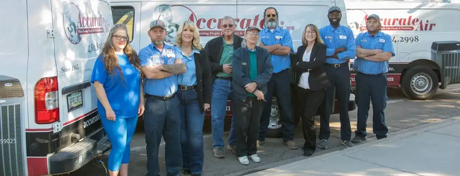 The Accurate Air team of nine standing together in front of two branded service vans