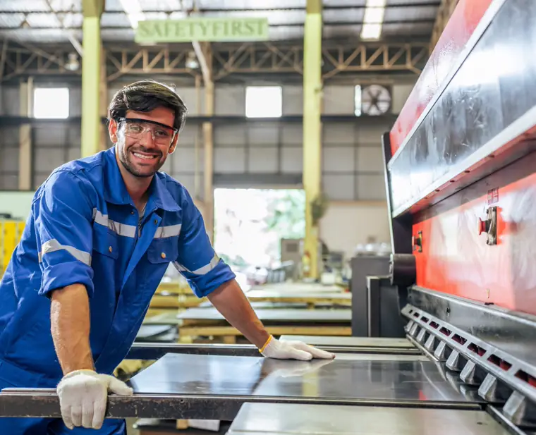A tradesperson working at a sheet-metal brake in a fabrication shop