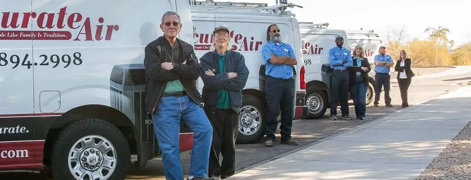 A line of Accurate Air service vans along a kerb with the team standing in front of them