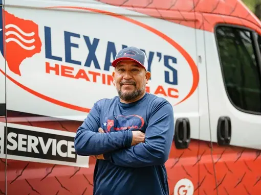 A Lexany&rsquo;s Heating & AC technician standing with arms crossed in front of the branded rear of a service van