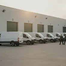 A row of identical white service vans at a fleet yard