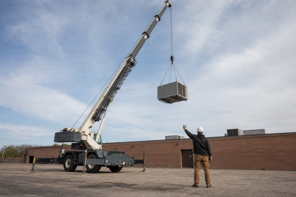 An operator standing in front of a mobile crane truck on a job site.