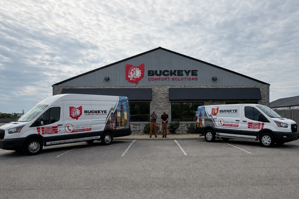 Two branded HVAC service vans parked outside a contractor’s building with two staff standing between them.