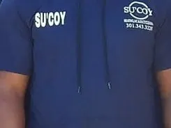 The Su&rsquo;Coy mark embroidered on a crew uniform shirt