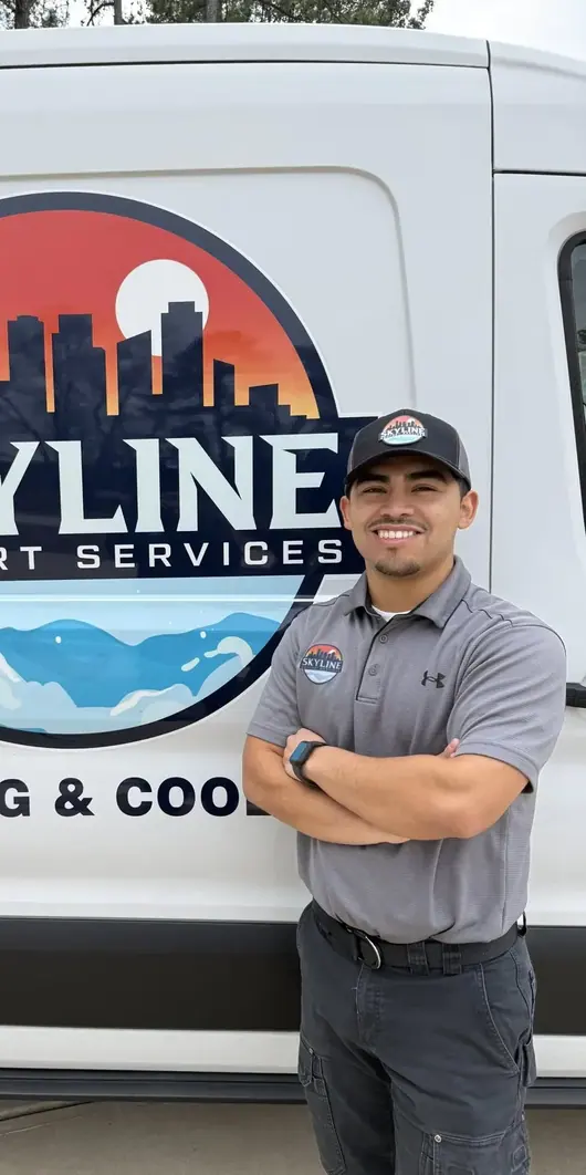 A Skyline Comfort Services technician standing with arms crossed beside a van carrying the Skyline logo