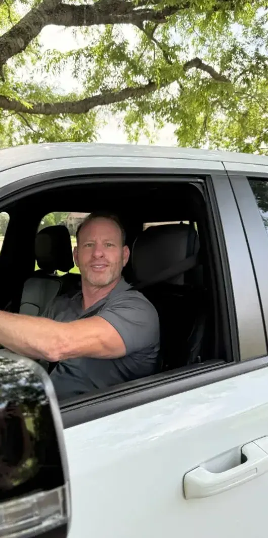 A technician sitting at the wheel of a white service van with the window down