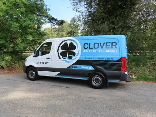 A Clover Air Duct Cleaning van parked on a tree-lined road